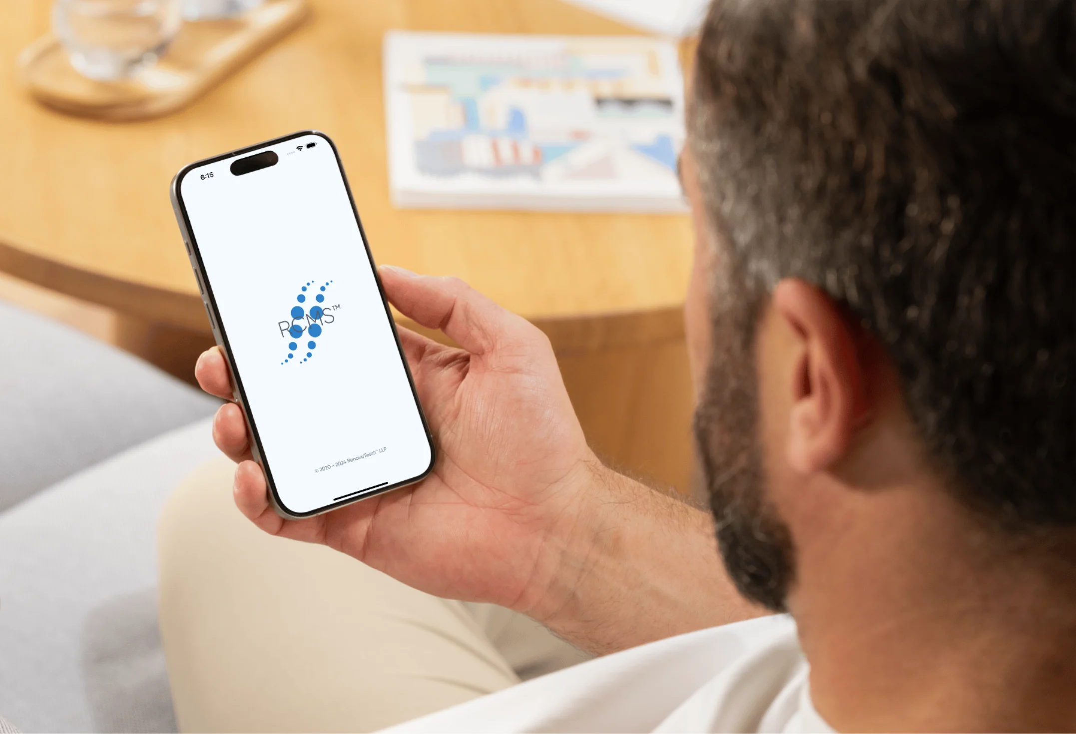 A man holding a smartphone displaying the RCMS® logo, highlighting the Voice-to-Dental Patient Record feature.